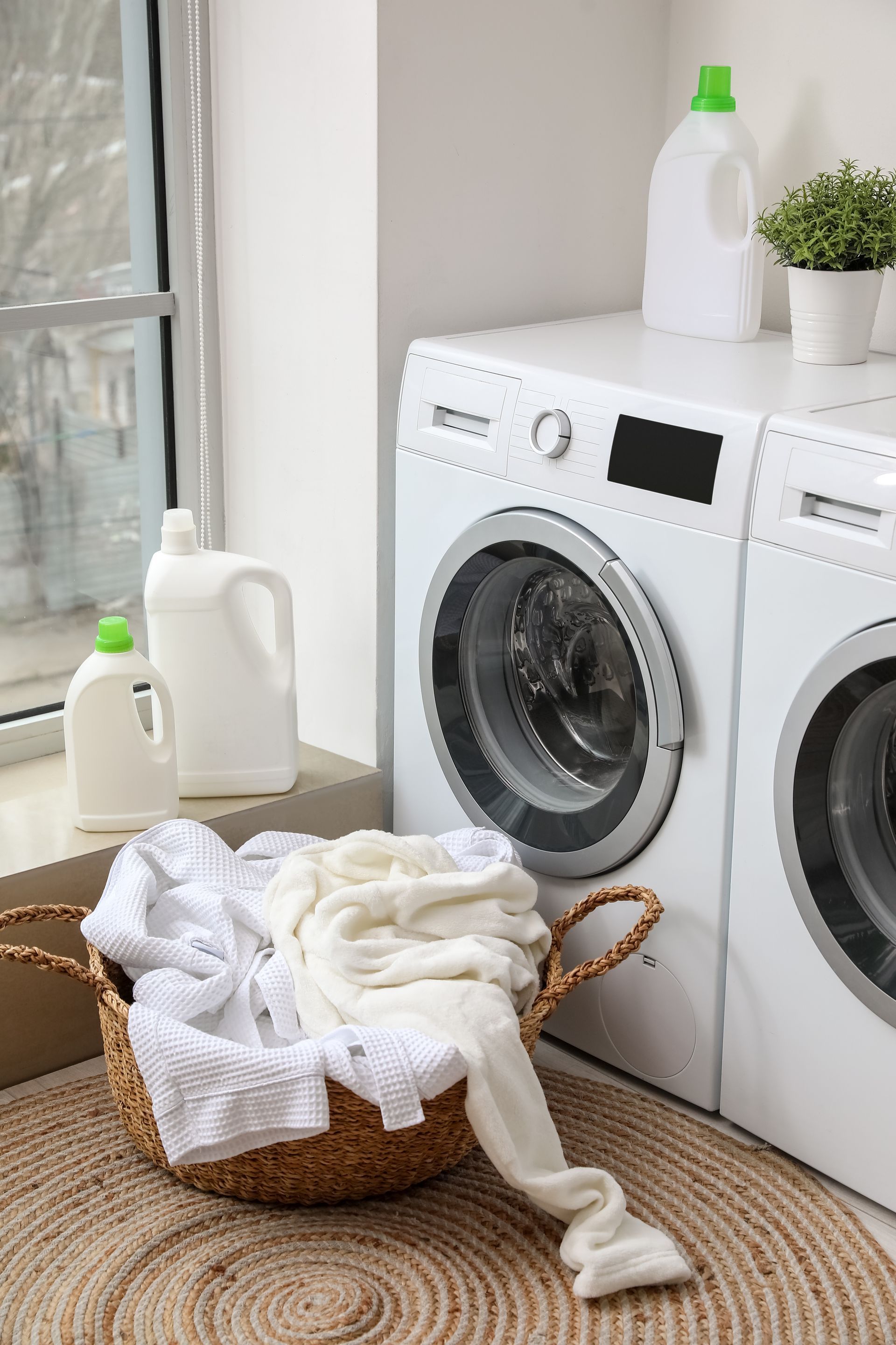 Laundry room with washing machine, laundry basket, and detergent bottles.