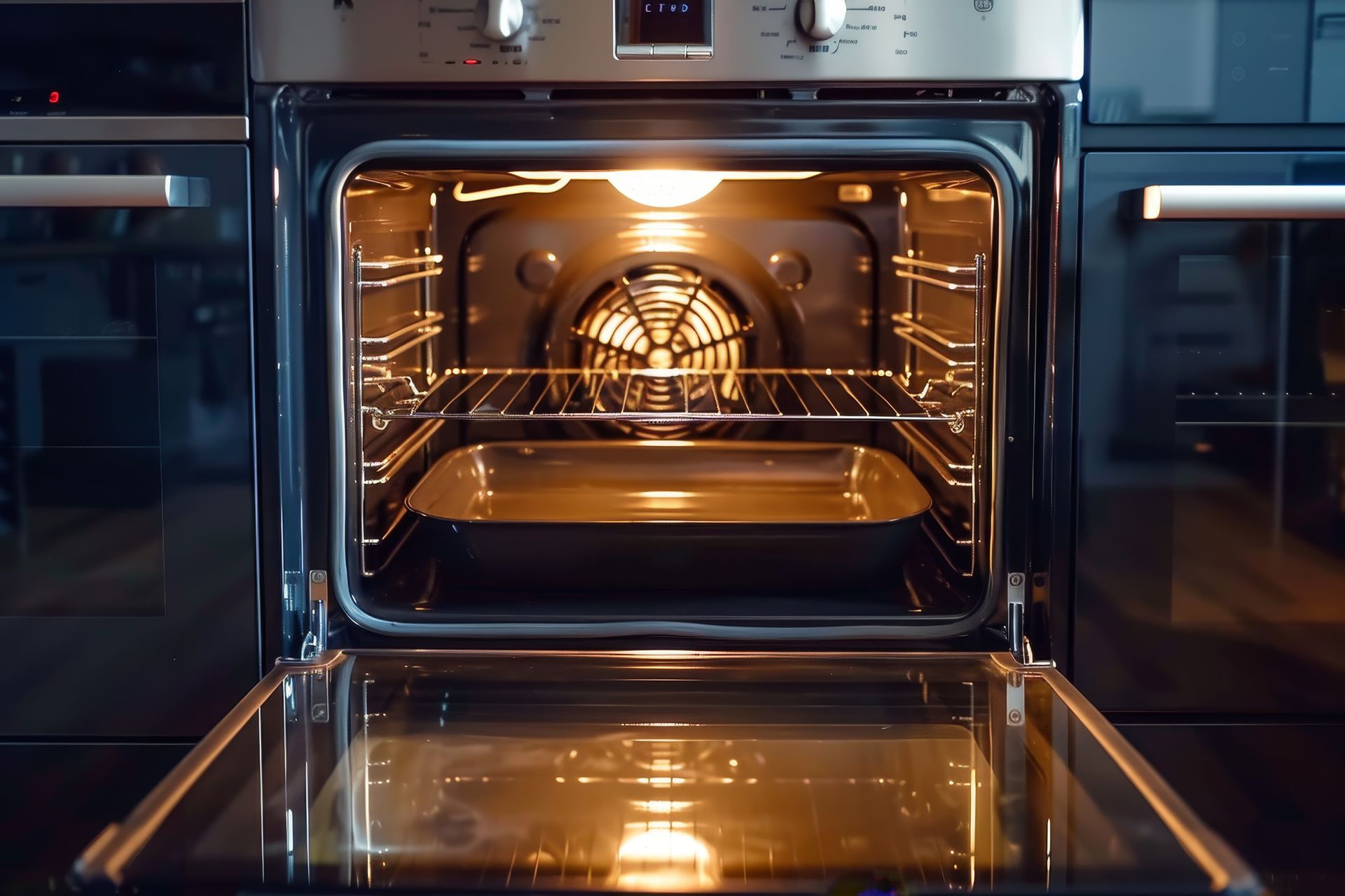 Opened electric oven with interior light on; baking tray on the bottom rack.