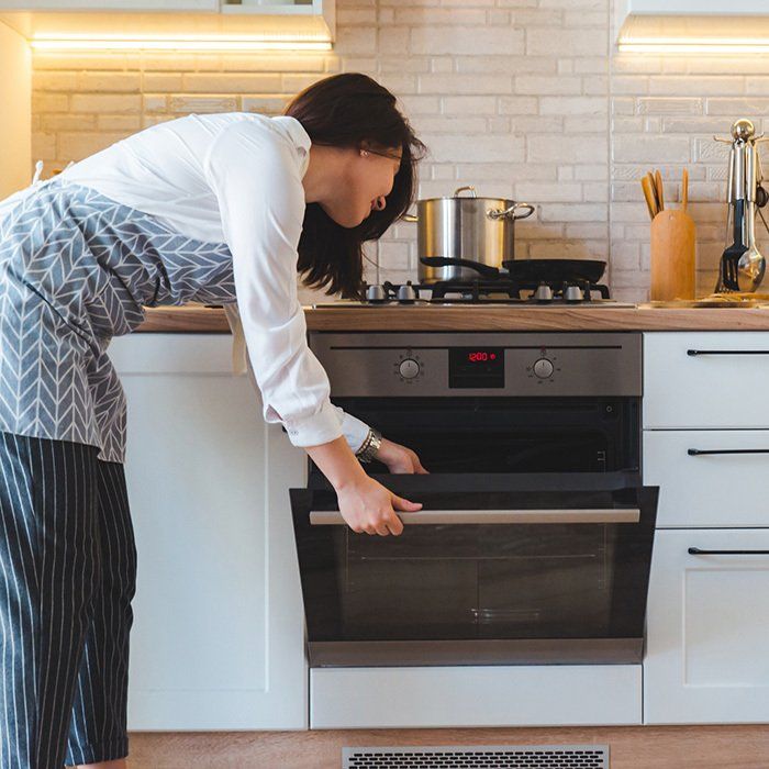 Woman Opening the Oven — Timberville, VA — Matt’s Appliance Service Inc
