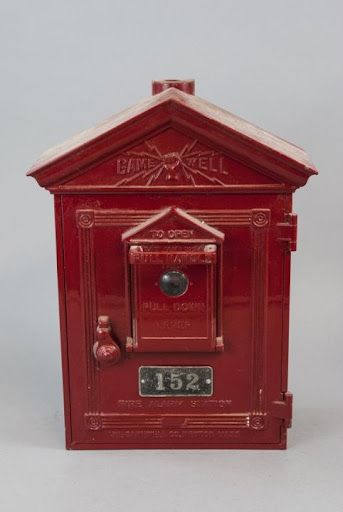 a red mailbox is sitting on a white surface .