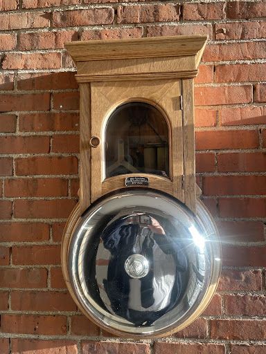 a wooden bell is hanging on a brick wall .
