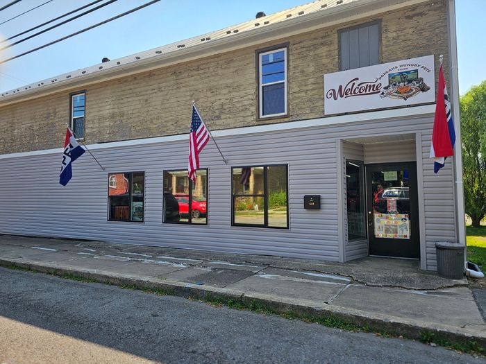 A brick building with a white siding and a sign that says welcome