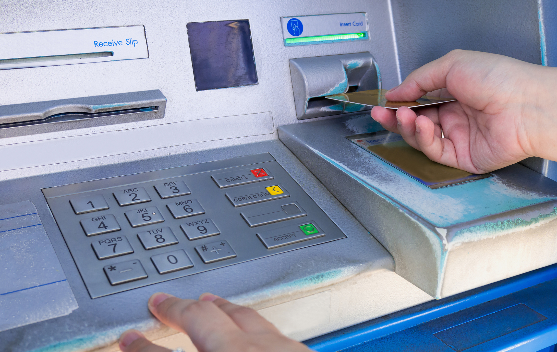 A person is inserting a credit card into an atm machine.