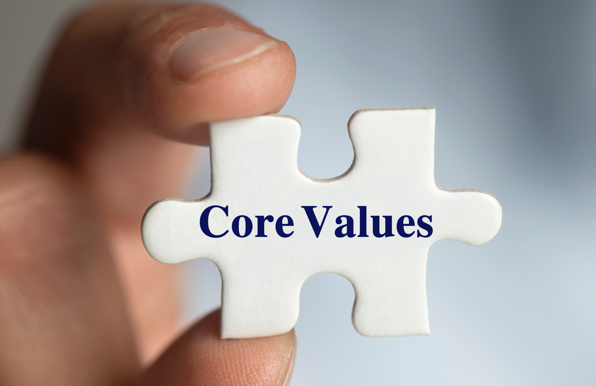 a person holding a puzzle piece with the word core value on it.