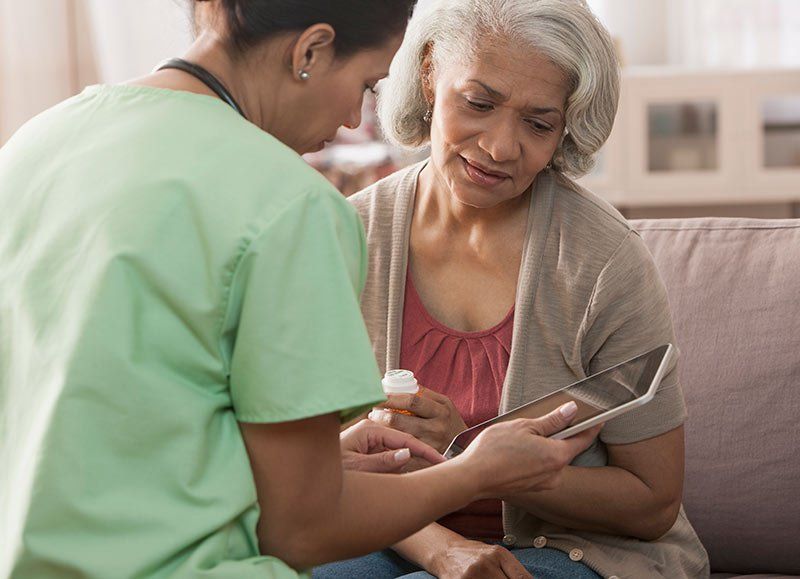 a nurse talking to a patient on a couch discussing high healthcare costs