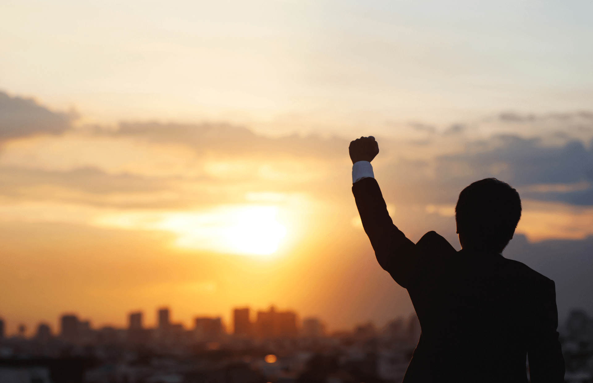 A person raising their arms in victory at sunset