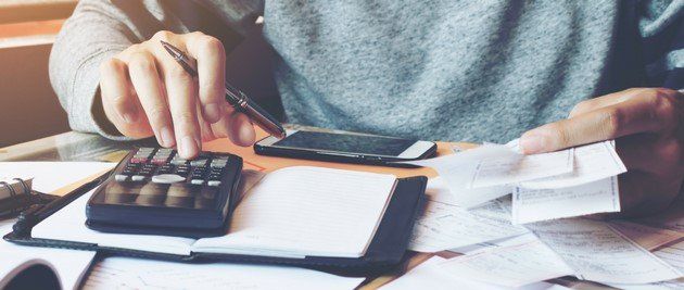 a person sitting at a desk with a calculator budgeting