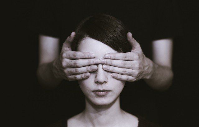 a man covering a woman's eyes with his hands.