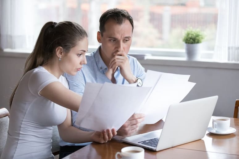 A man and woman sitting at a table looking at their financial papers