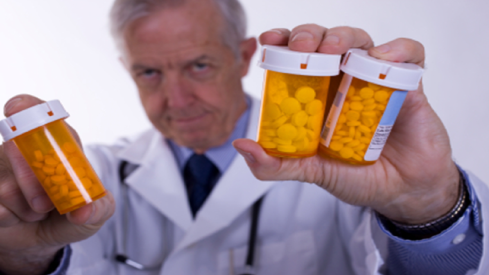 a doctor in a white coat holding three bottles of pills.