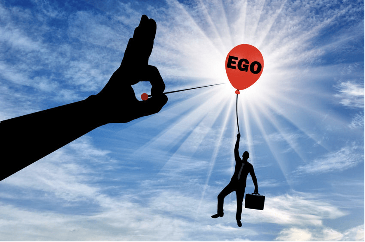 a person about to pop a ballon that a person is holding onto with the word ego on it.