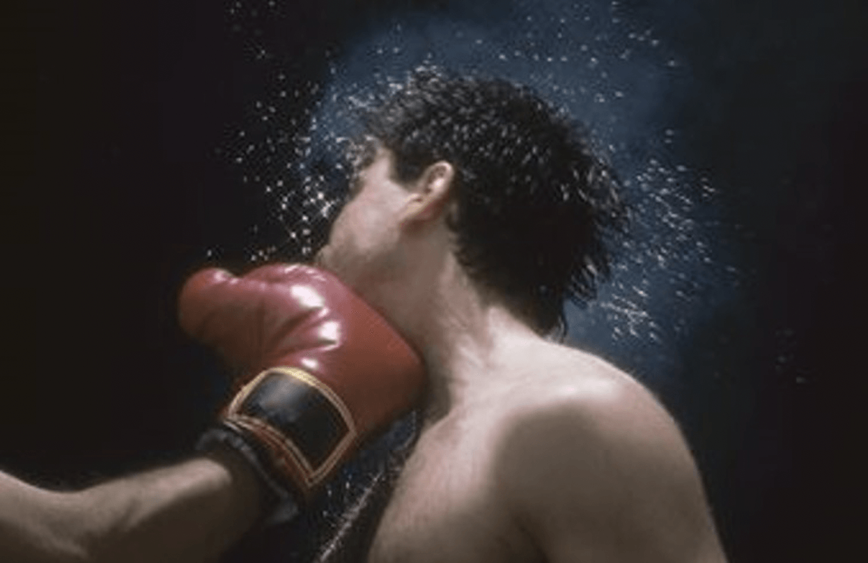 A boxer getting punched by a man wearing red boxing gloves