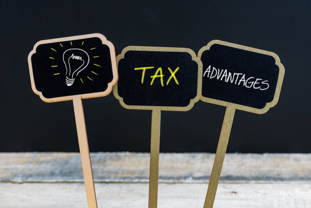 three small wooden signs with a lightbulb the word tax and the word advantage written on them.