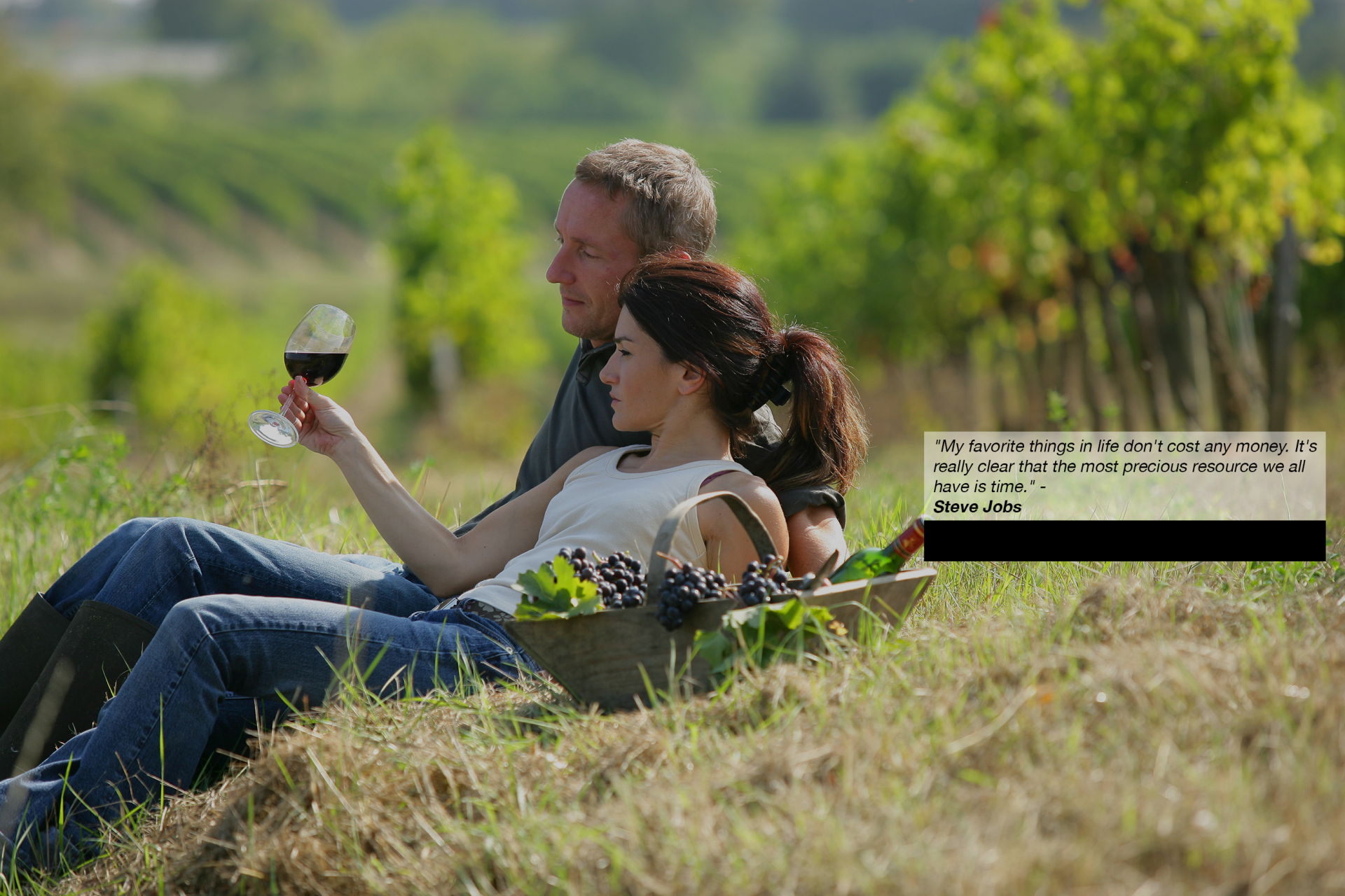 a man and woman sitting in a field with a glass of wine living their Ideal Life