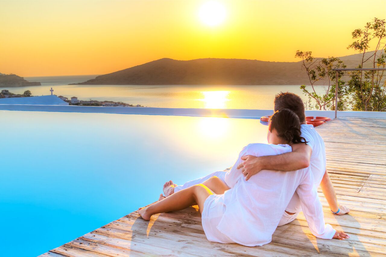 Couple Living the Ideal Life Watching the Sunset Beside A Pool on Vacation