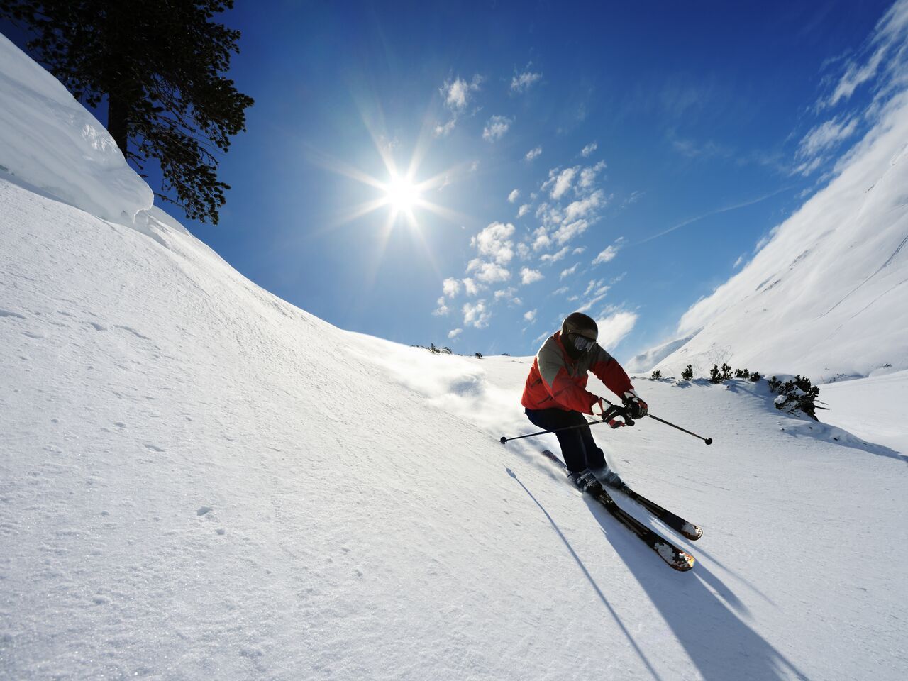 Person living their ideal life skiing downhill on a sunny day