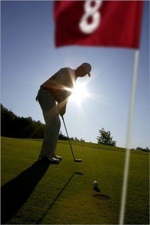 A man playing golf in front of a red flag living his ideal life
