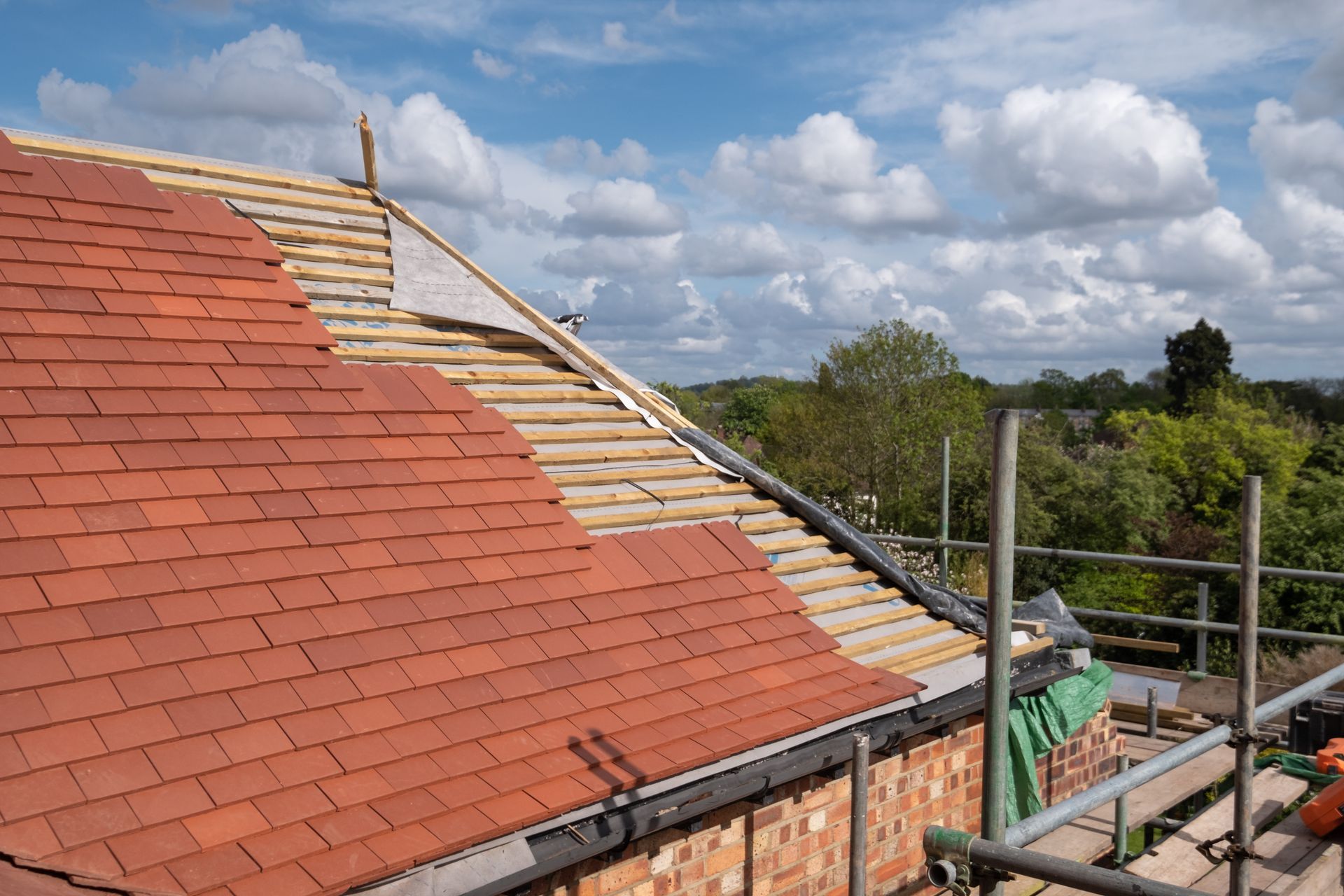 A red tiled roof is being installed on a house.