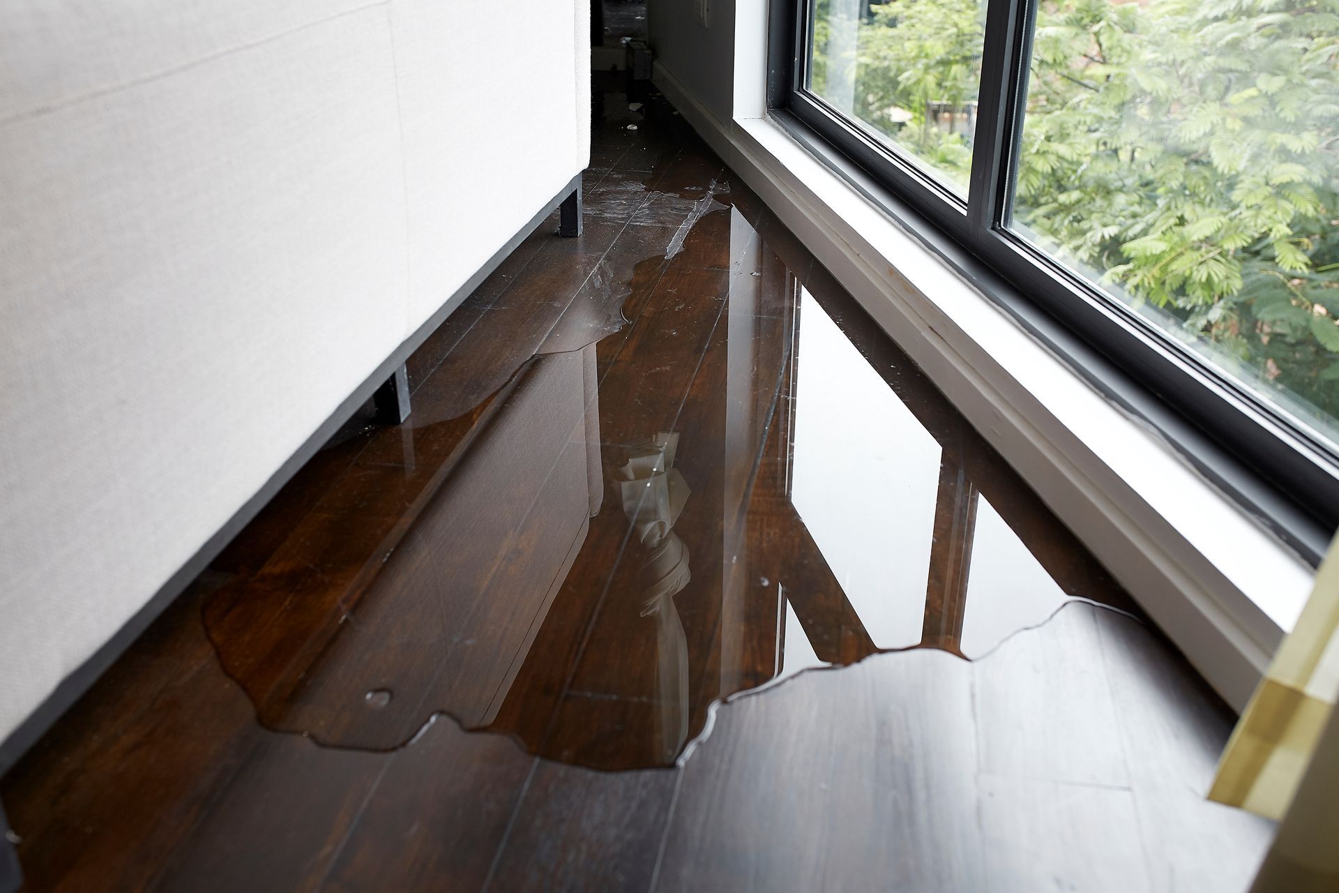 A room with a window and a puddle of water on the floor