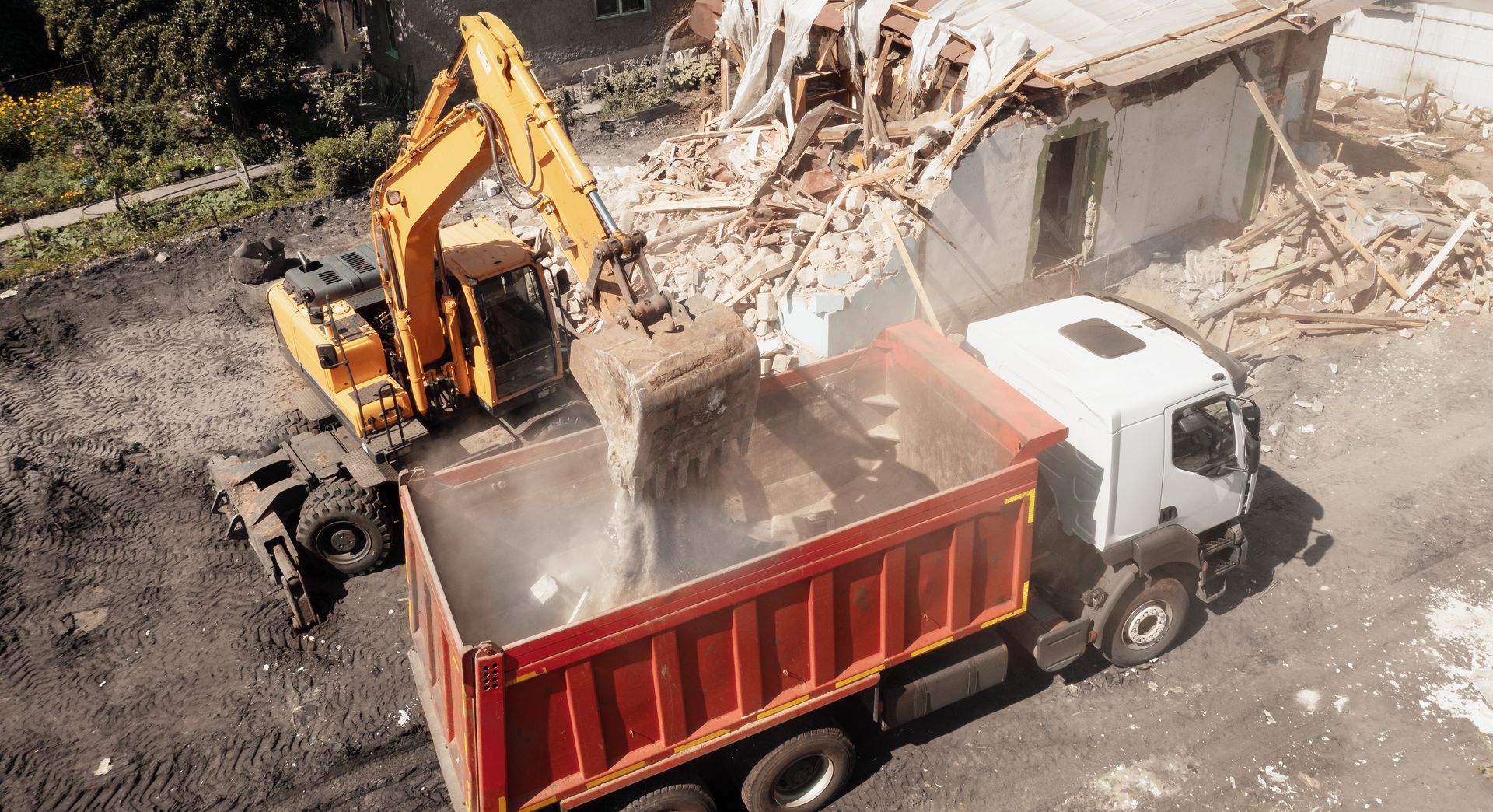 An excavator is loading rubble into a dump truck.