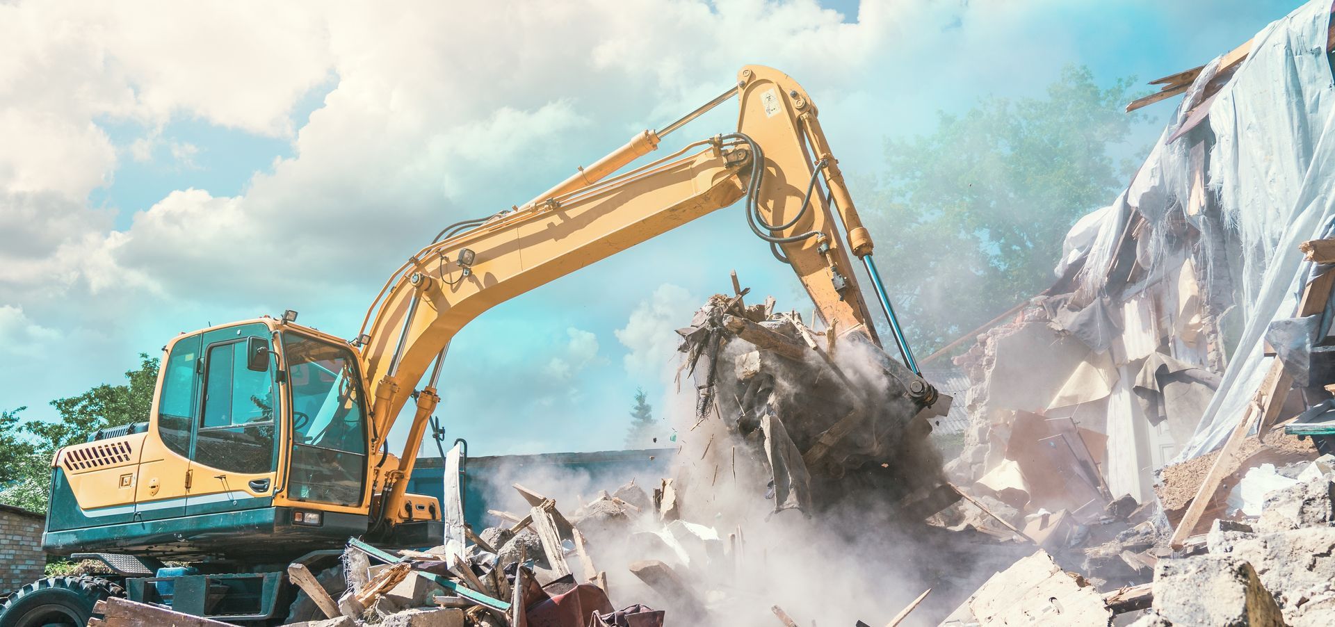 A yellow excavator is demolishing a building.