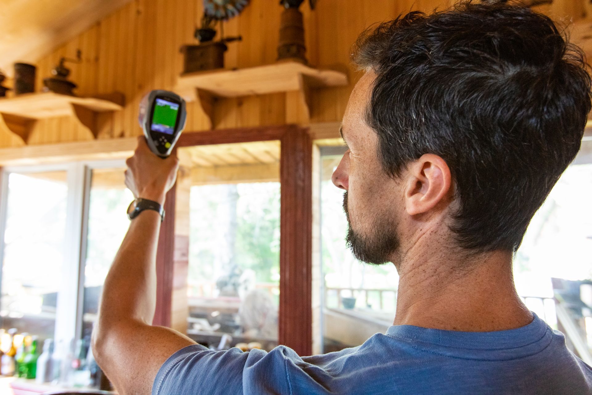 A man is holding a thermometer in his hand in a room.