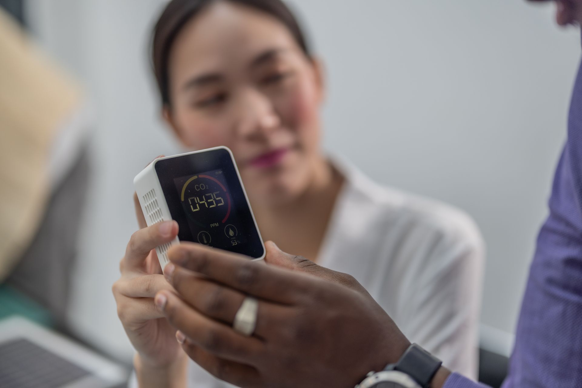 A man is holding a cell phone in front of a woman.