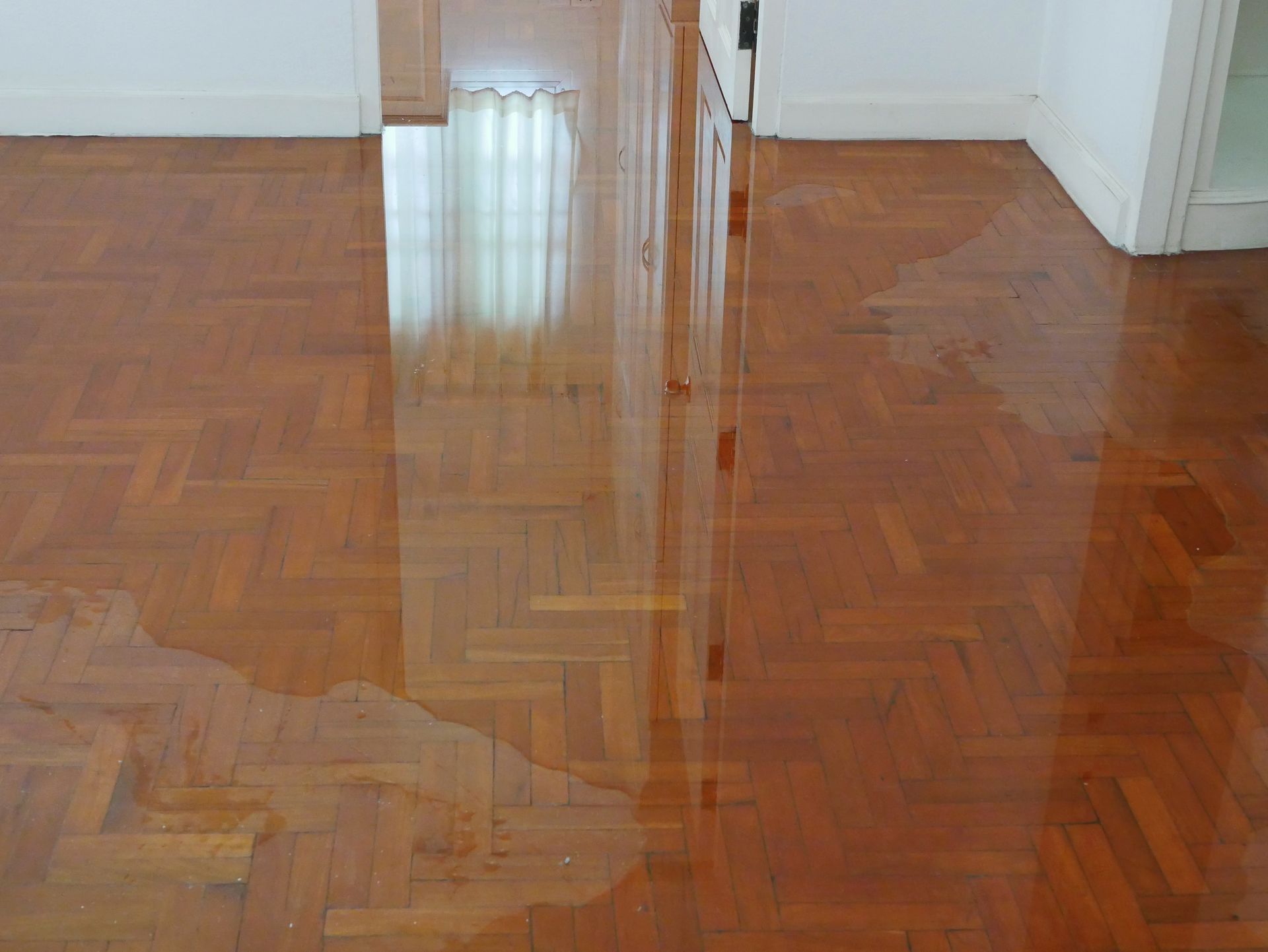 A wooden floor in a room with a reflection of a window.