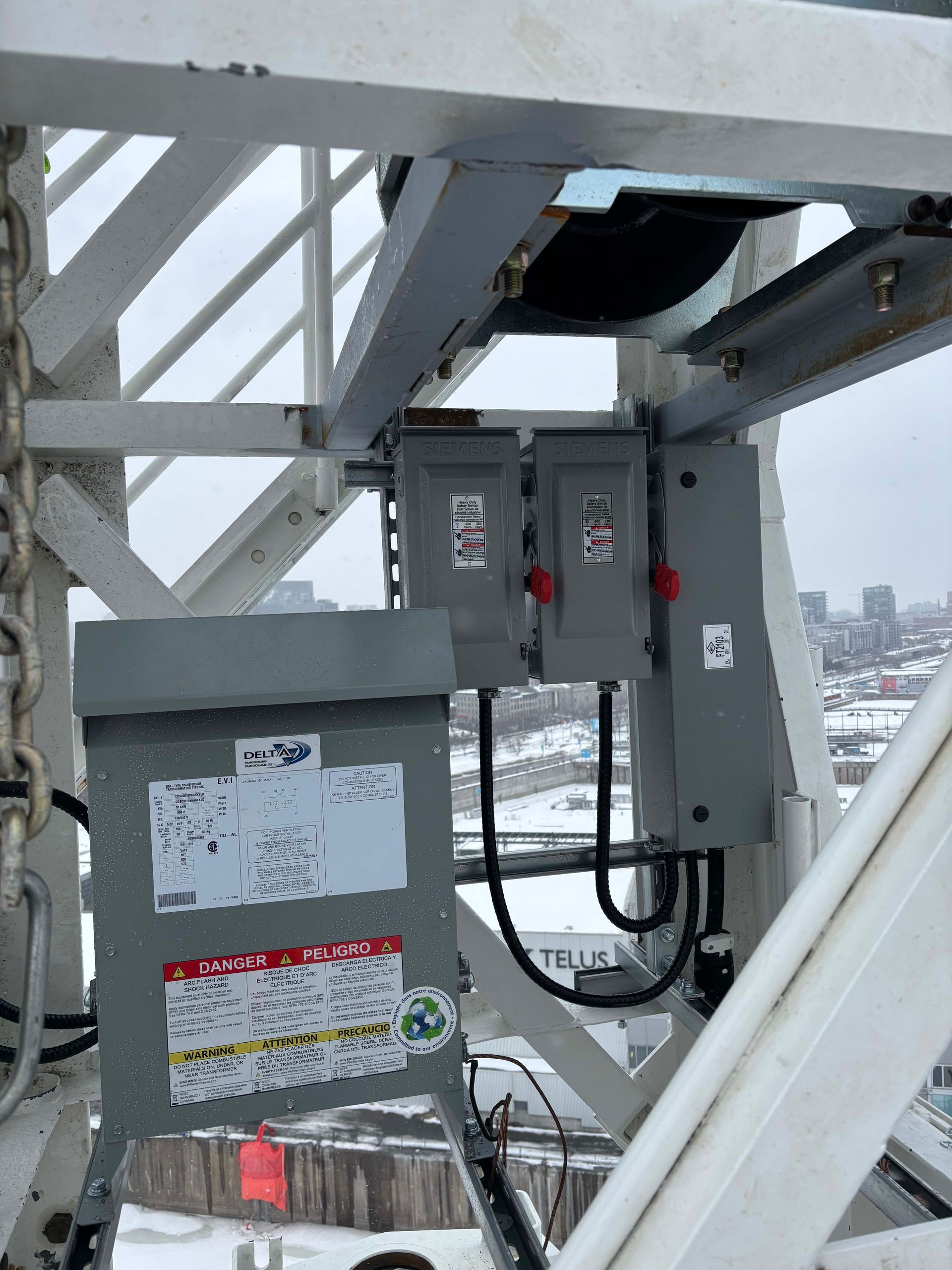 Coffrets et panneaux électriques montés sur une structure de grue, probablement pour la distribution d'énergie sur un chantier de construction.
