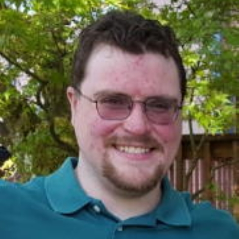 A man with a beard and glasses is smiling for the camera.