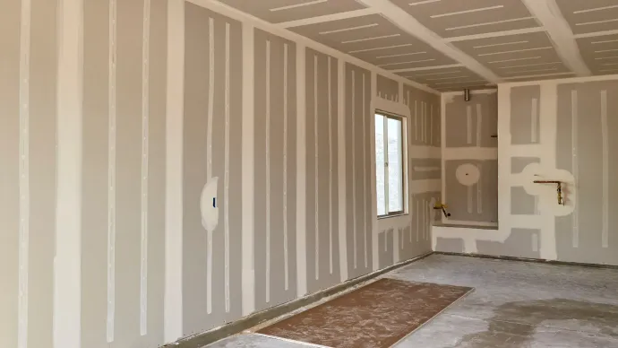 Interior room under construction, drywall installed on walls and ceiling.