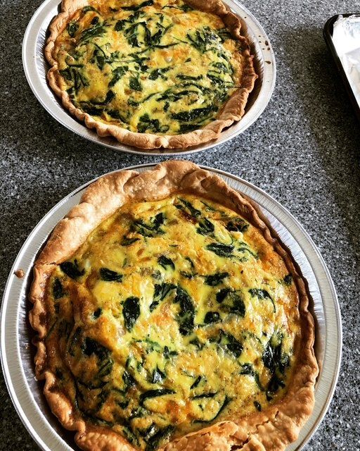 Two spinach quiches in foil tins.