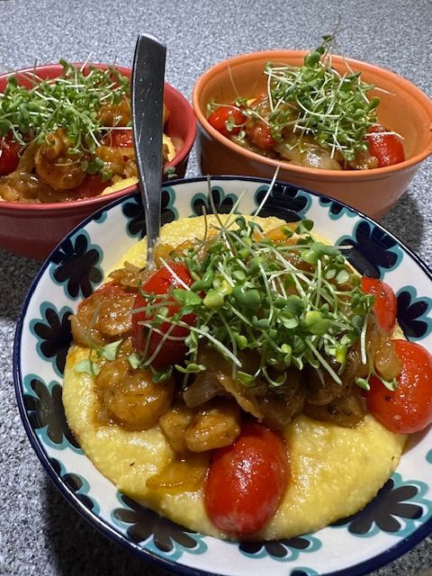 Bowls of shrimp and grits topped with microgreens.