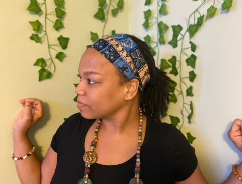 Mortar and pestle with sprig of purple flowers and green foliage on wooden surface.