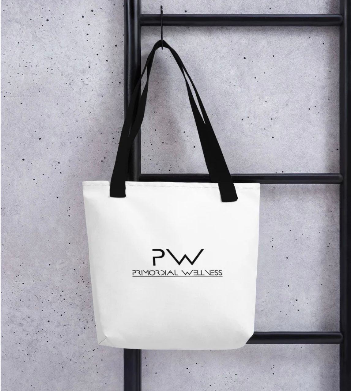 White tote bag with black handles hanging on a black metal rack. The bag has a black 