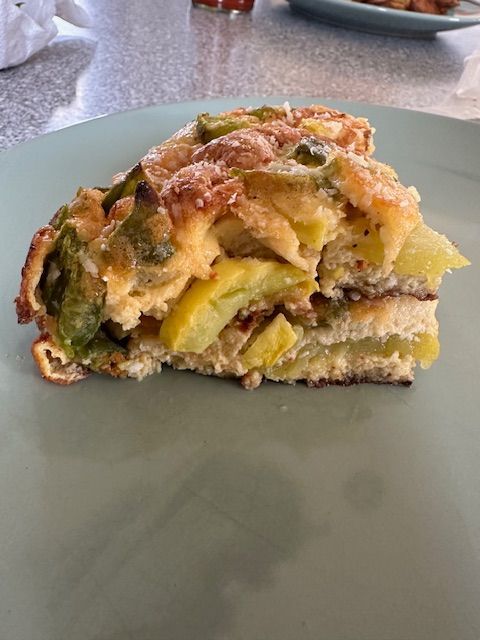 Slice of a squash frittata with green peppers on a green plate.