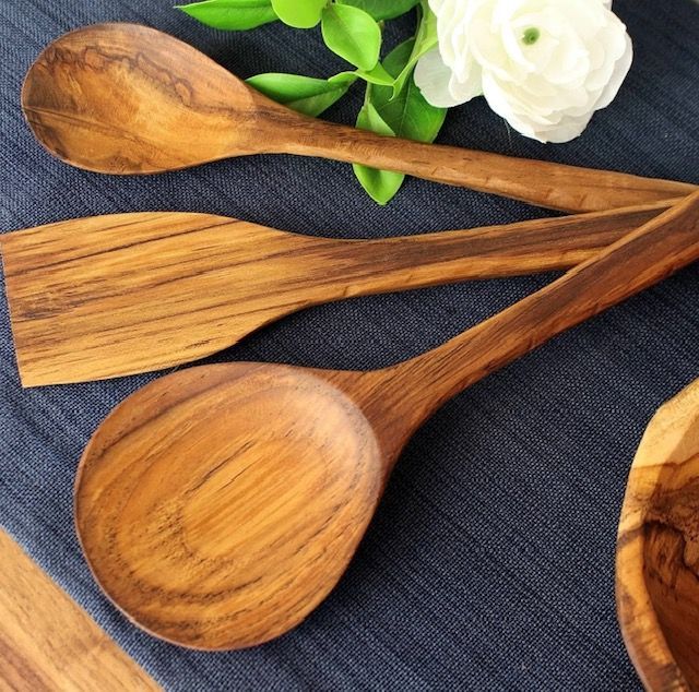 Wooden spoons and spatula on a blue cloth, near white flowers and greenery.