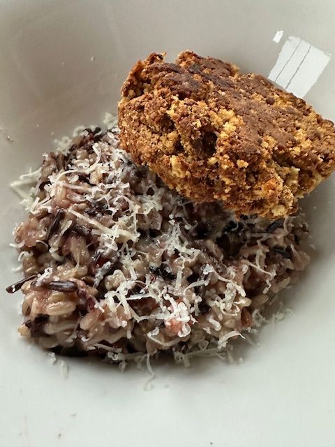 Risotto with shredded parmesan and a breaded topping in a white bowl.