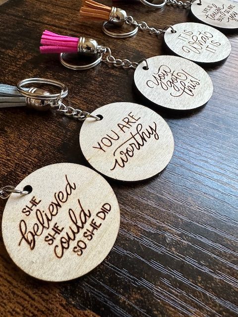 Wooden keychains with inspirational quotes, each with a colorful tassel.