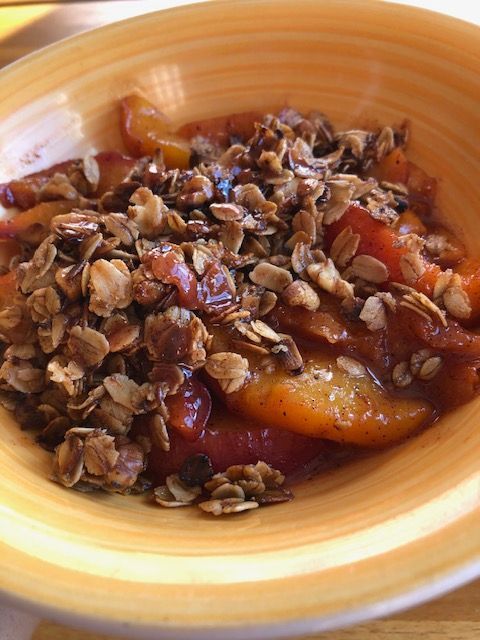 Apple crisp in a yellow bowl, with a crunchy oat topping.