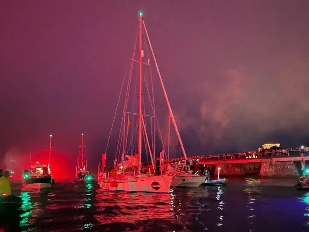 A group of sailboats are docked in a harbor at night.
