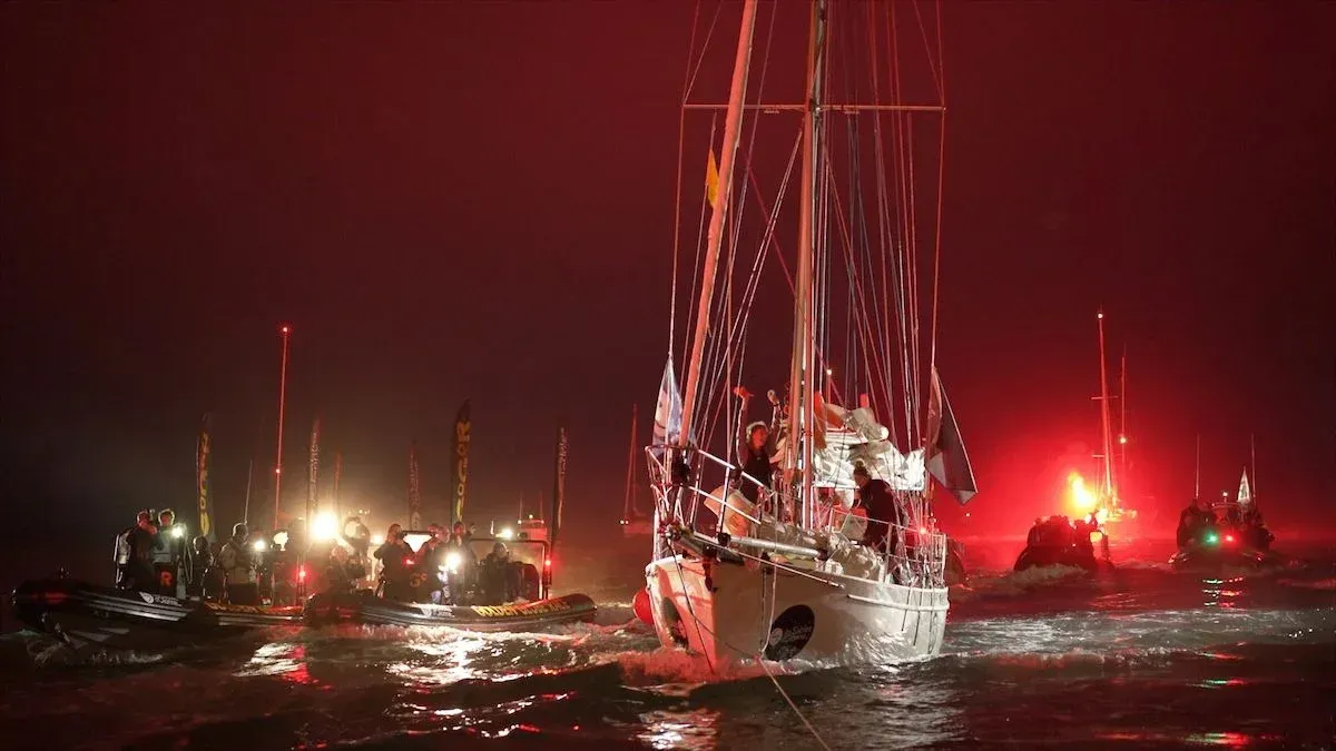 A group of sailboats are in the water at night.