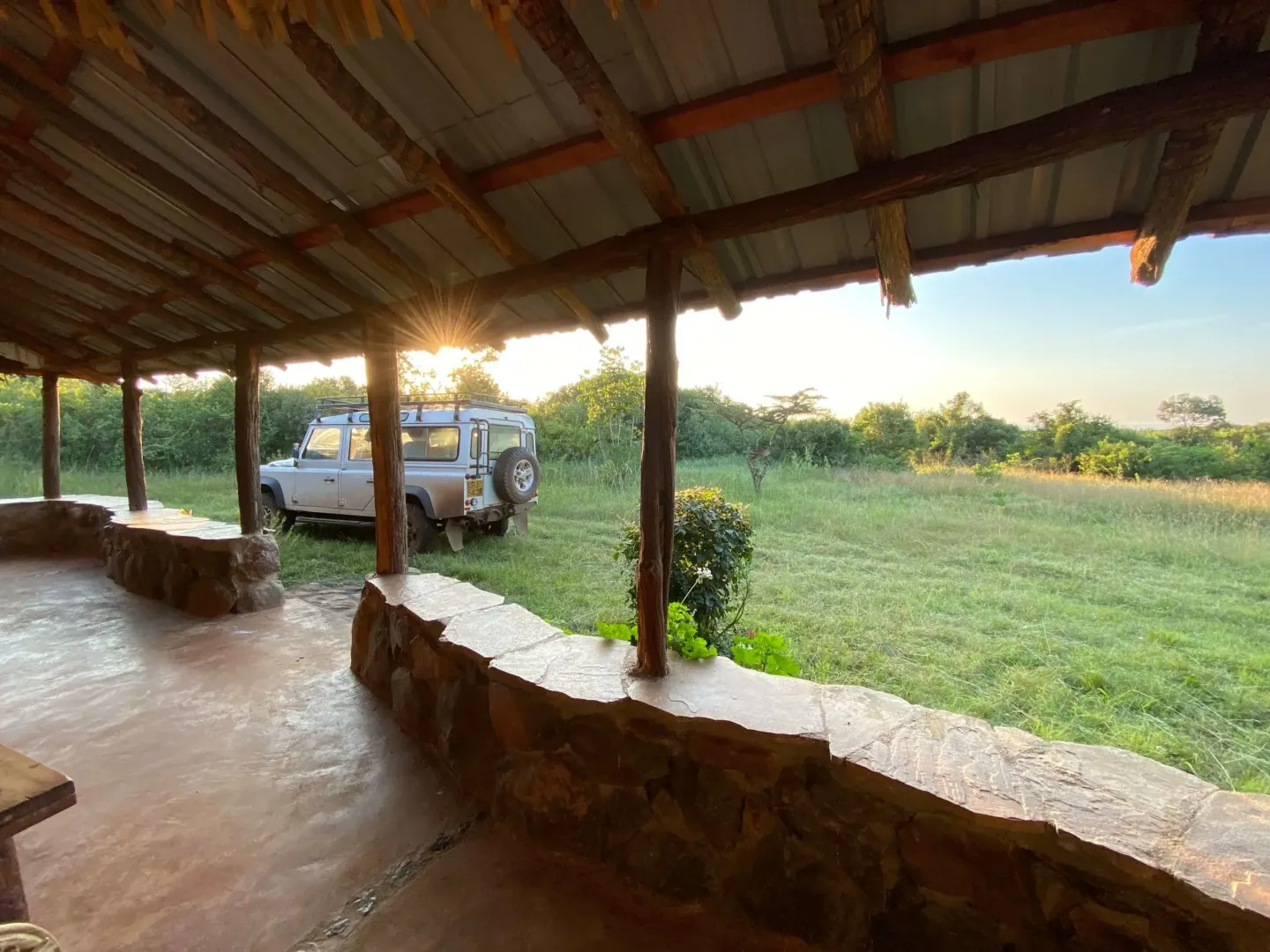 A car is parked in a field under a covered area.