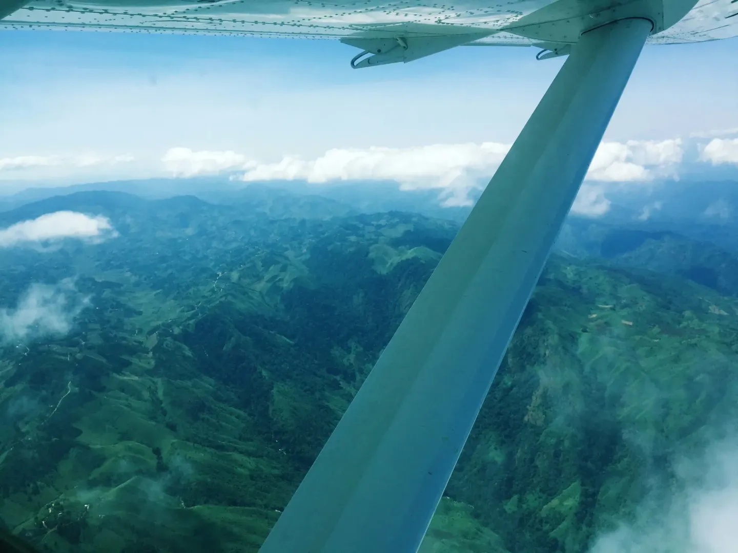 A plane is flying over a mountain range with clouds