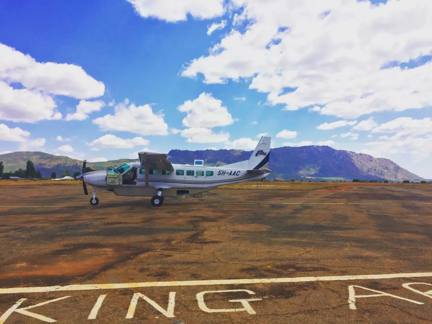 A small plane is parked on a runway with the word king written on the ground.