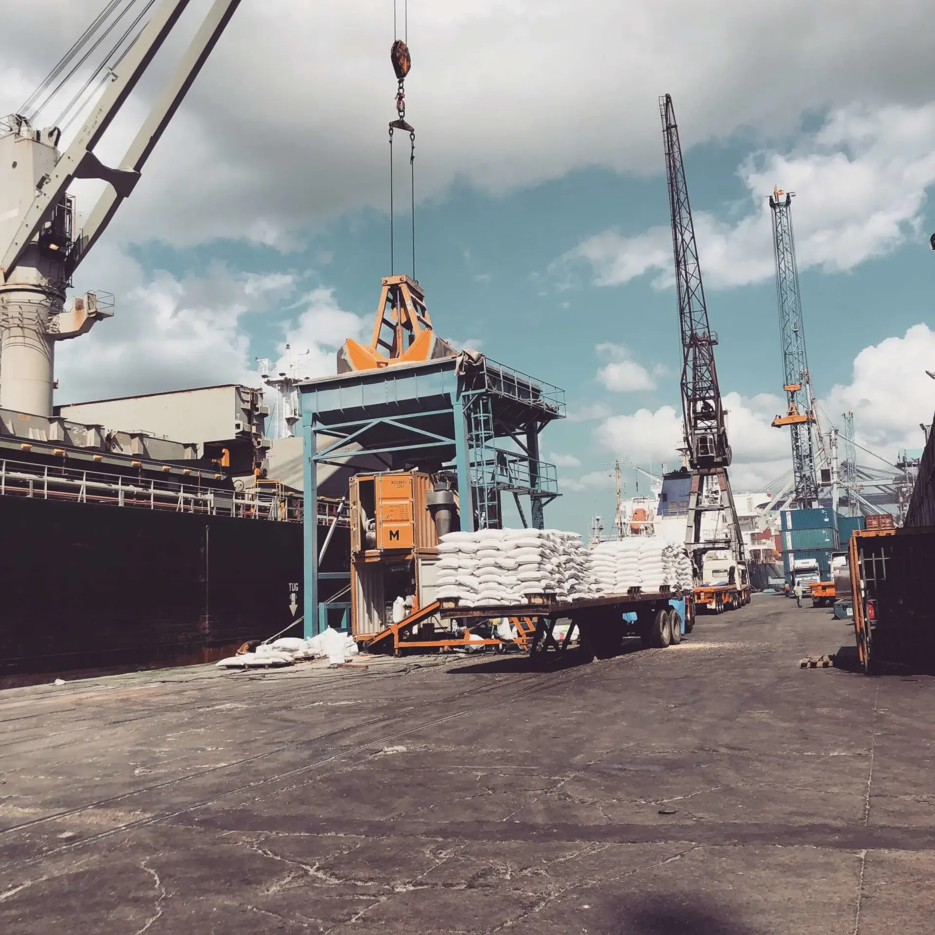 A large ship is being loaded with cargo by a crane