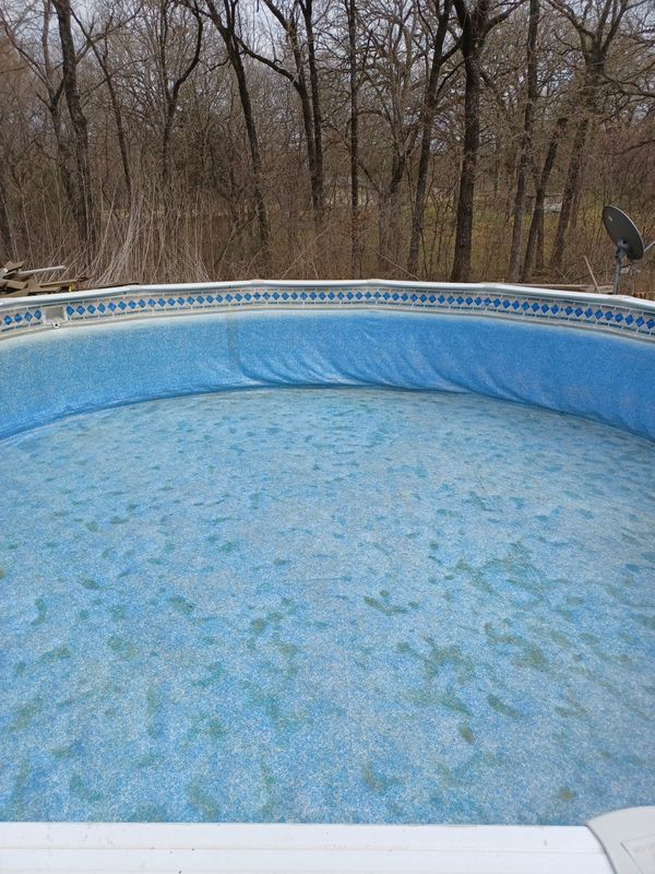An empty, above-ground circular swimming pool with a light blue liner, viewed