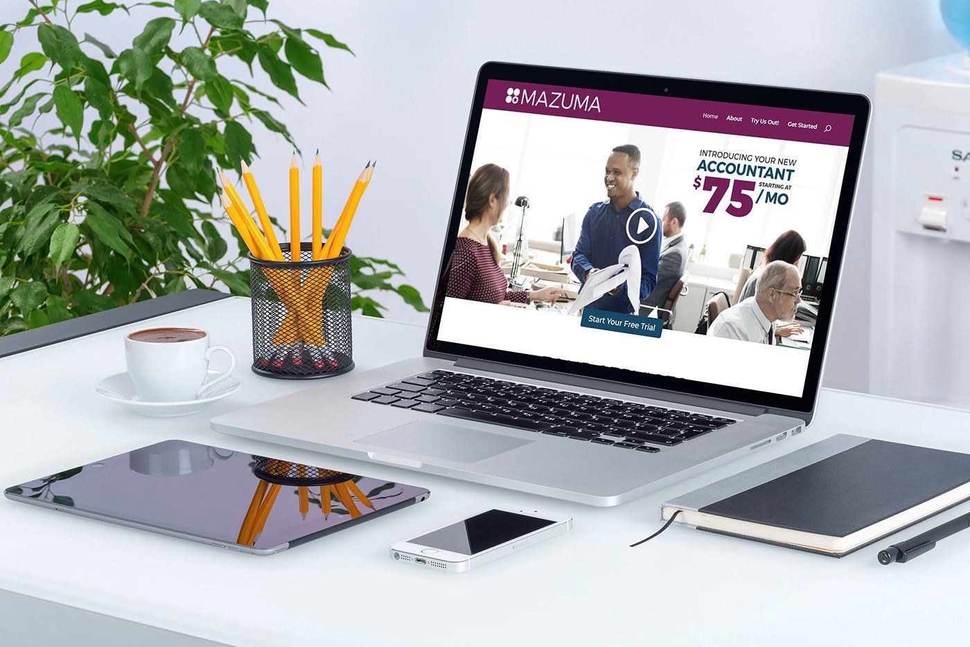 Modern desk with laptop, tablet, phone, pencil cup, and plant; laptop shows a sports website
