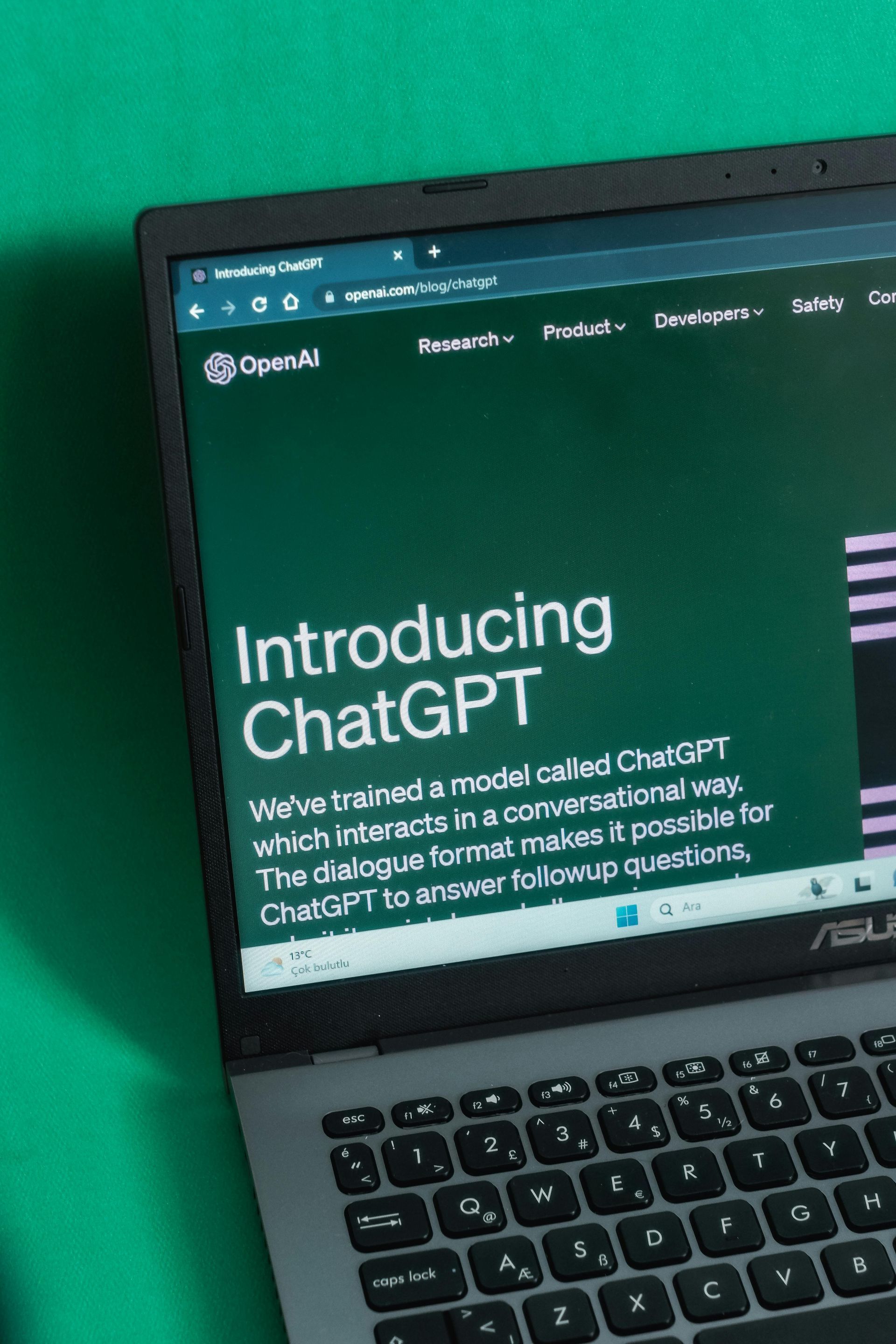 Laptop showing OpenAI’s “Introducing ChatGPT” webpage on a green background