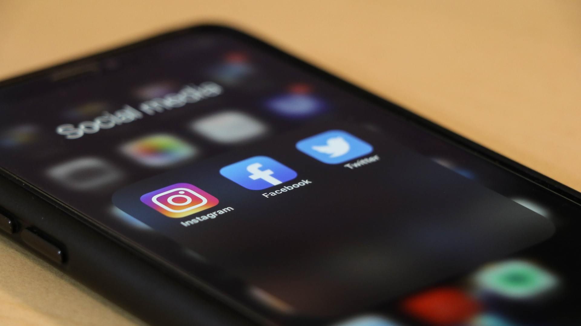 Smartphone screen showing social media app icons, including Instagram, Facebook, and Twitter, on a dark background